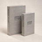 Σετ δύο γκρι κουτιών βιβλίων Design Story σε πλάγια όψη, με λινή επένδυση και ορατές ράχες